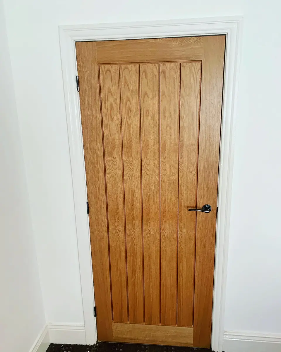 Oak vertical-plank internal door hung in a white architrave, an example of the internal doors we supply and fit in Newcastle